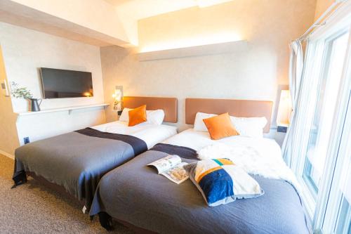 大阪市にあるApartment Hotel 11 Umedaのテレビ付きのホテルの部屋にベッドが2つある