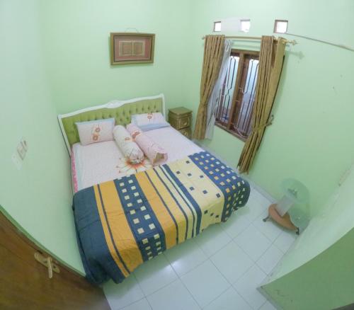 - une petite chambre avec un lit et une couverture colorée dans l'établissement Grand Berbah Homestay Jogja, à Potrojayan