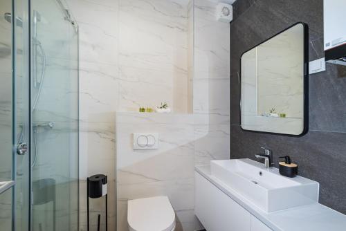 een witte badkamer met een wastafel en een douche bij Apartment Dalmo Views in Zadar