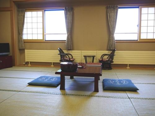 a room with a table and chairs and windows at KKR Kawayu in Teshikaga