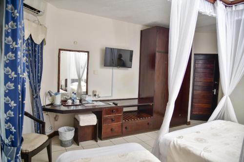 a bedroom with a desk and a mirror and a bed at North Coast Beach Hotel in Kikambala