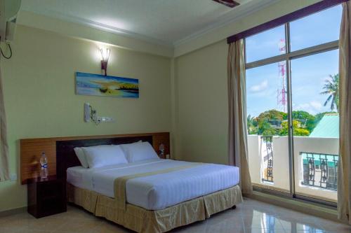 a bedroom with a bed and a large window at Maaniya Residence in Maamigili