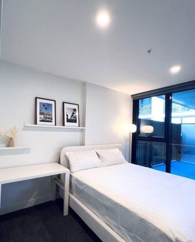 a white bedroom with a bed and a window at Anthem Stylish 1BR Apartment - with top amenities and easy airport access in Melbourne