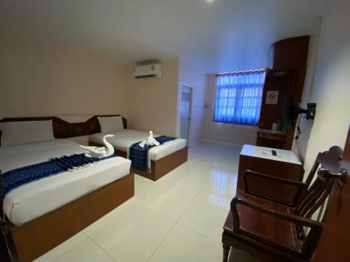 Un dormitorio con 2 camas y una silla. en Imperial Sakon Hotel, en Sakon Nakhon