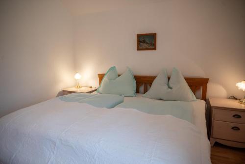a bedroom with a white bed with two pillows at Haus Seegarten in Grundlsee