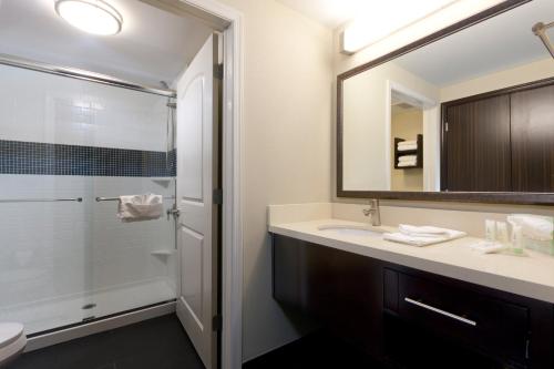 a bathroom with a shower and a sink and a mirror at Staybridge Suites Buffalo-Amherst by IHG in Amherst