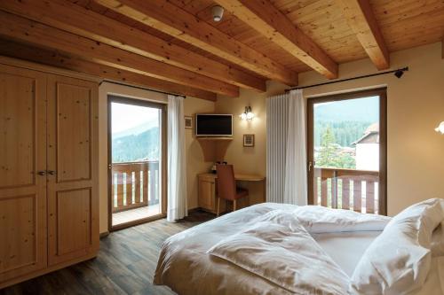 sypialnia z łóżkiem i balkonem w obiekcie B&B La Montanara w mieście San Martino di Castrozza