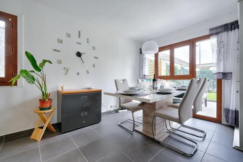une salle à manger avec une table et une horloge au mur dans l'établissement Le 44 - Appt avec jardin privé, à Ris-Orangis