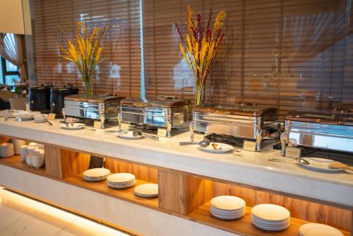 a buffet line with white plates on a table at Northern Charm Hotel in Ho Chi Minh City