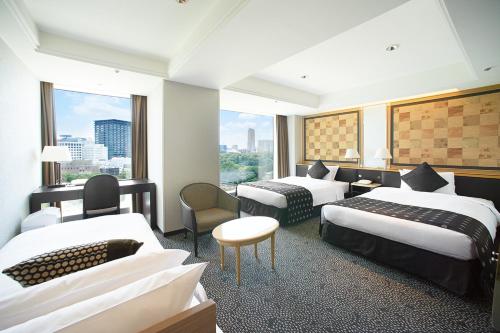 a hotel room with three beds and a window at Hotel New Otani Tokyo The Main in Tokyo