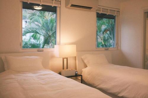 a bedroom with two beds and a lamp and a window at Aloha Beachfront ホノルル - Hawaii Kai in Honolulu