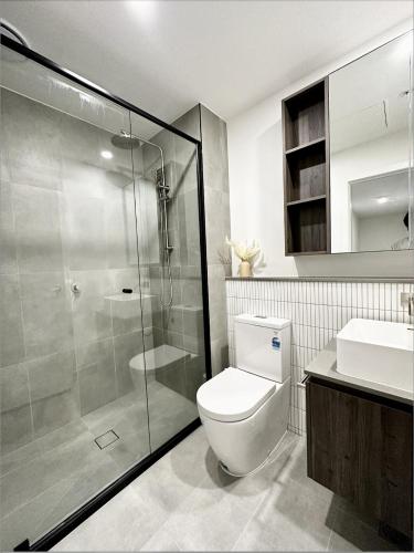 a bathroom with a shower and a toilet and a sink at Anthem Stylish 1BR Apartment - with top amenities and easy airport access in Melbourne