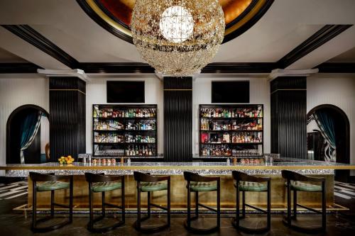 a bar with green chairs and a chandelier at Grand Bohemian Orlando, Autograph Collection in Orlando