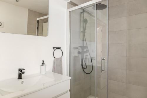baño blanco con ducha y lavamanos en Arrábida Guest Studio, en Aldeia Rica