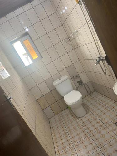 a bathroom with a toilet and a window at AU COEUR DE BONAMOUSSADI-WIFI-PARKING-GARDIENS-24H in Douala