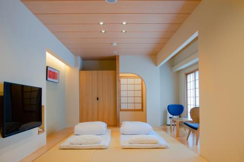 a room with three beds and a tv at Yuno Yado Shoei in Kyoto