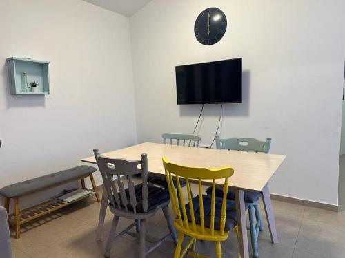 a dining room table with chairs and a clock on the wall at רגע של מדבר in Yeroẖam