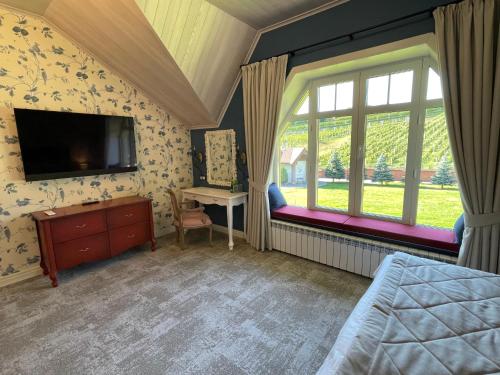 um quarto com uma cama, uma televisão e janelas em WineGarden em Mukacheve