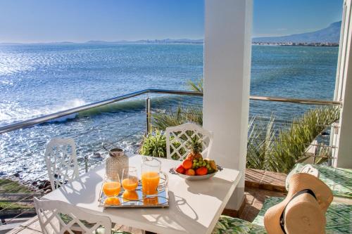 a table with a bowl of fruit and glasses of orange juice at 185 on BEACH Boutique Suites in Gordonʼs Bay