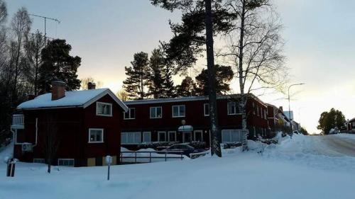 Une grande maison rouge avec de la neige au sol dans l'établissement Hostel Gästhem Glassen Apartment, à Rättvik