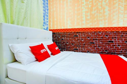 a white bed with two red pillows on it at Tangkak Mawadahh Inn Stay in Tangkak