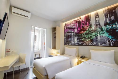 una habitación de hotel con 2 camas y un cuadro en la pared en Cleo Hotel Jemursari Surabaya, en Surabaya