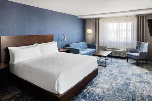 a hotel room with a large bed and chairs at Four Points by Sheraton Edmonton South in Edmonton