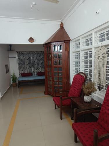 a living room with red chairs and a couch at Coomaaoon by silversky in Gonikoppal