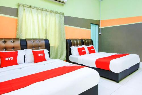 two beds in a room with red and white pillows at Tangkak Mawadahh Inn Stay in Tangkak