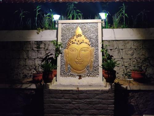 a statue of a head on a wall with plants at Coomaaoon by silversky in Gonikoppal