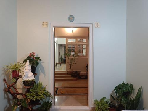 a hallway with a door leading into a room with potted plants at Coomaaoon by silversky in Gonikoppal
