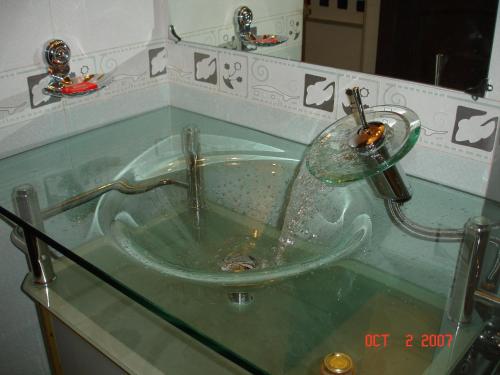Un lavabo de cristal con grifo en un baño. en Raj Niwas, en Udaipur