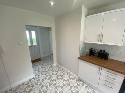 a kitchen with white cabinets and a tile floor at Spacious Contemporary Home in Leeds