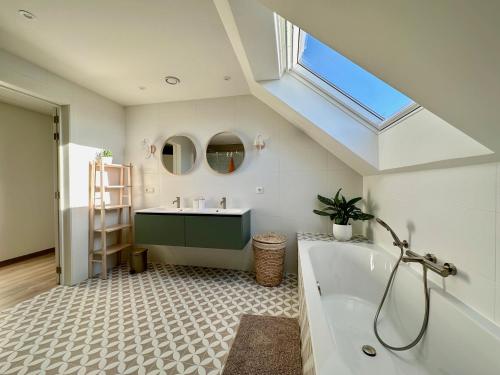 łazienka z wanną, umywalką i oknem dachowym w obiekcie Villa Vief Lommel w mieście Lommel