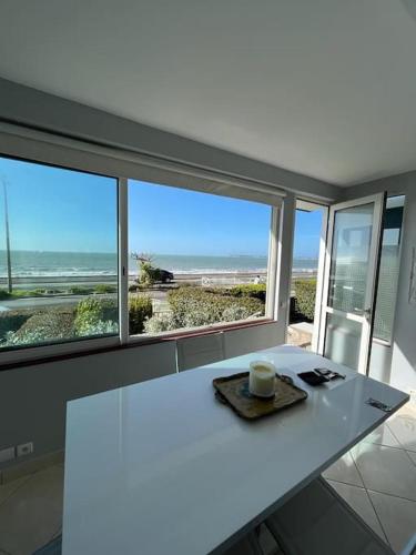 - une table blanche dans une chambre avec vue sur l'océan dans l'établissement APPARTEMENT FACE MER, à La Baule