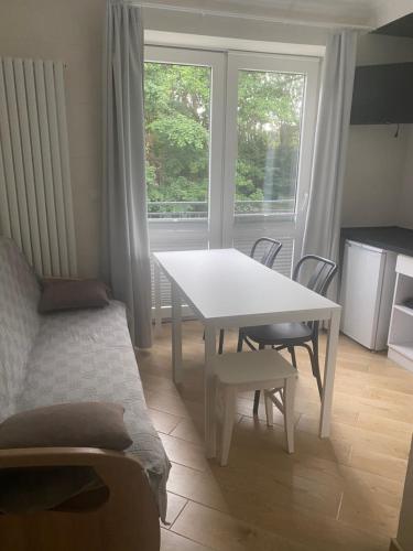 een witte tafel en stoelen in een kamer met een raam bij Pokoje gościnne Orlovo DT in Gdynia