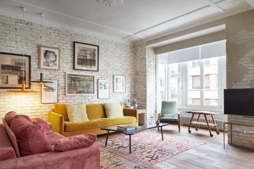 a living room with a yellow couch and a brick wall at Dear Oldie Apartment by FeelFree Rentals in San Sebastián