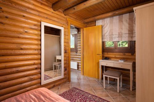 a bedroom in a log cabin with a desk and a mirror at Natura Chalets in Méga Khoríon