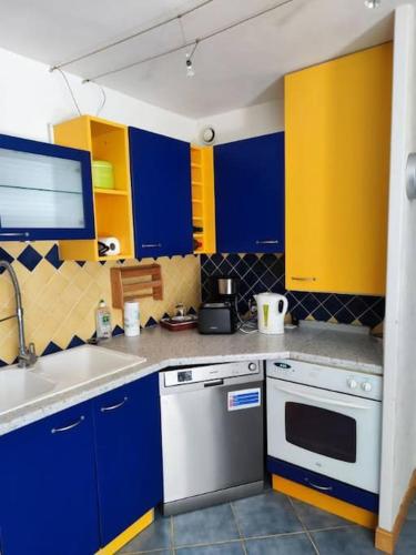 une cuisine avec des placards bleus et jaunes et un évier dans l'établissement appartement rez de jardin 6 personnes cagnes sur mer 06 piscine et tennis, à Cagnes-sur-Mer