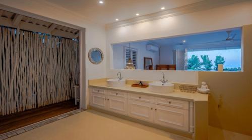 a bathroom with two sinks and a large mirror at The Salty Nest in Umdloti