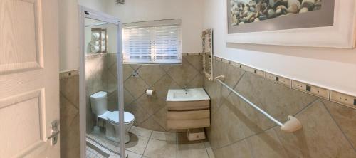 a bathroom with a toilet and a sink at Fiddlewood Beach House in Port Shepstone