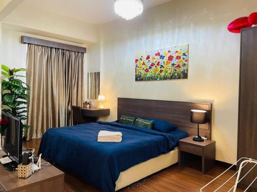 a bedroom with a blue bed and a television at Anastays Studio & Apartment Suite with Free 2 & 4 Waterpark Tickets at Bayou Lagoon Resort in Ayer Keroh