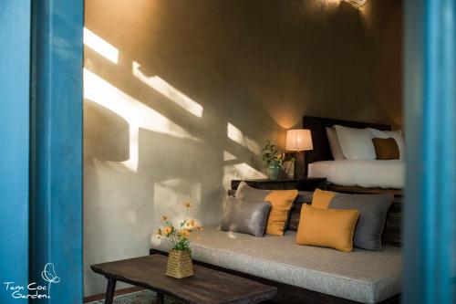 a bedroom with a bed and a couch with pillows at Tam Coc Garden Resort in Ninh Binh