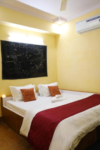una camera da letto con un grande letto con cuscini rossi e bianchi di Urmila Homestay a Jaisalmer