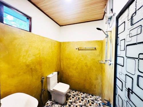 baño con aseo y pared amarilla en Nature Bliss Villa, en Aluthgama