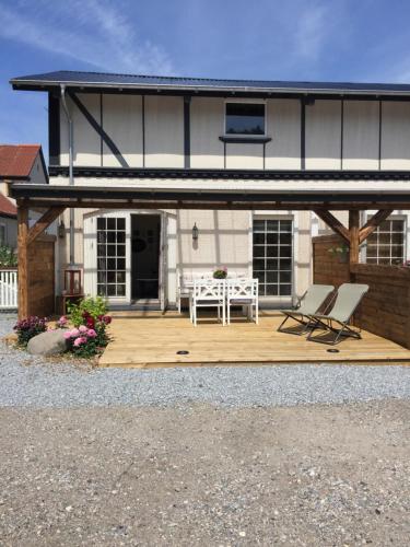 a house with a deck with two chairs and a table at Frederiksensminde Bed & Breakfast in Marrebæk