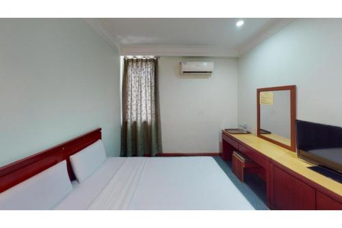 a bedroom with a bed with a mirror and a dresser at OYO 90847 Hotel Asia City in Kota Kinabalu
