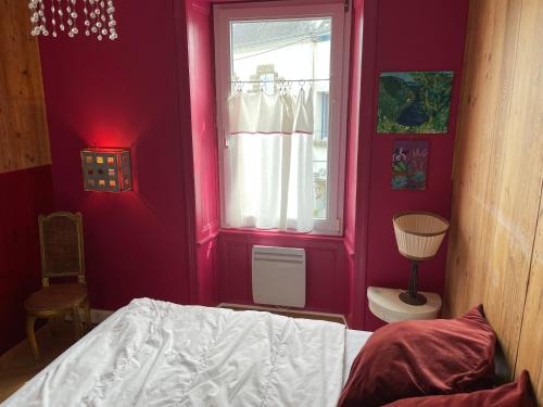 Schlafzimmer mit rosa Wänden, einem Bett und einem Fenster in der Unterkunft Maison de famille sur l'île de Groix in Groix