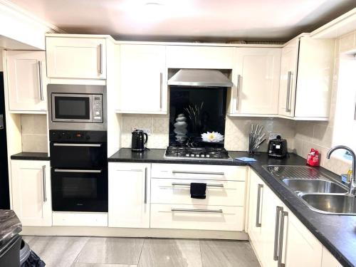 a kitchen with white cabinets and black appliances at Ensuite Room Platinum 1 Harborne - Quinton Road in Birmingham