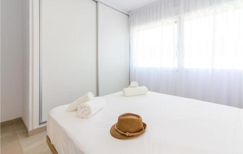 - un chapeau assis au-dessus d'un lit blanc dans l'établissement Stunning Apartment In Denia With Kitchen, à Dénia